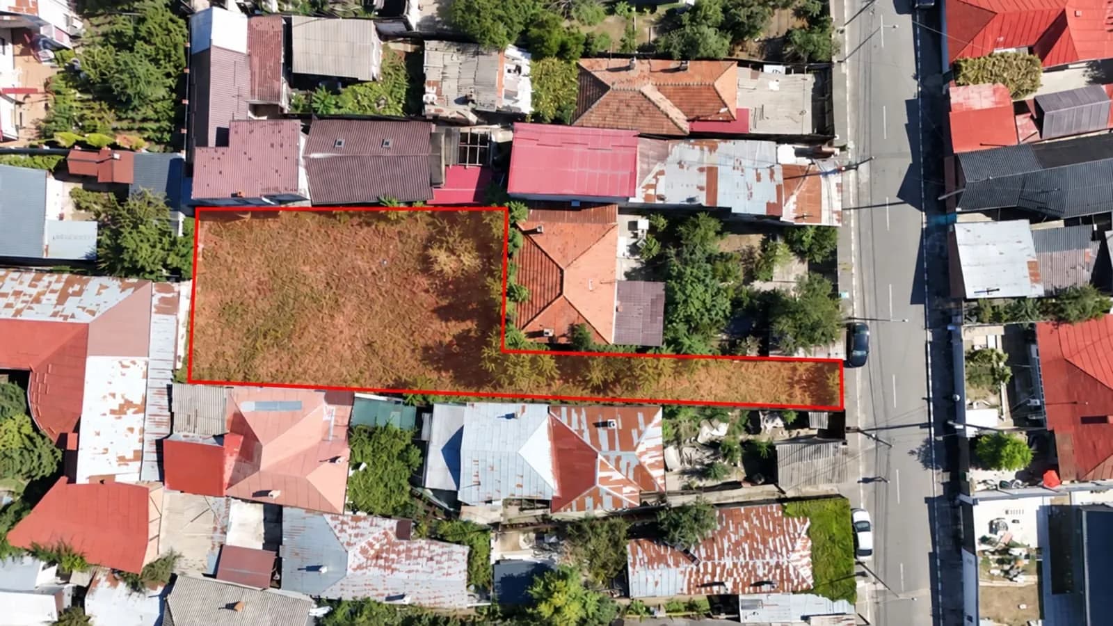 Teren din zenit, cu construcții vecine, acoperiș roșu
