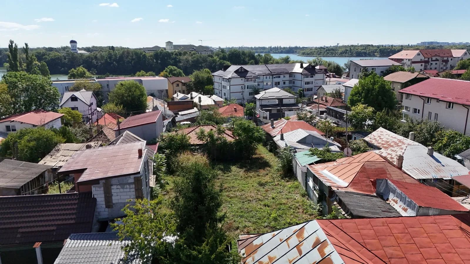 Vedere din teren către zonă, case și lac