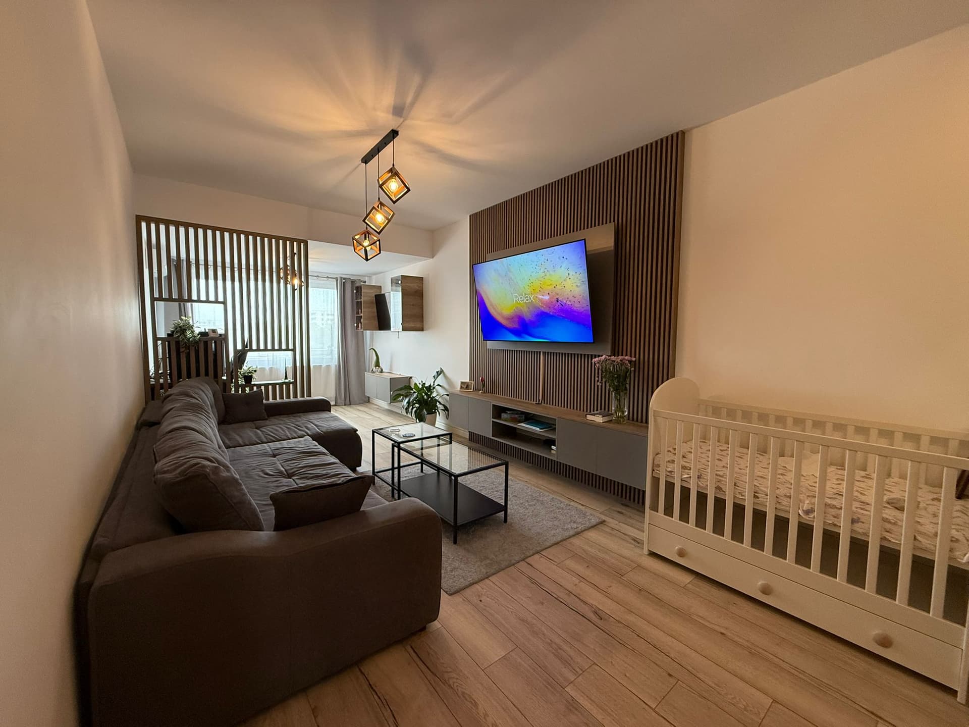 Apartament, 2 camere, de vânzare, Brâncoveanu — Living cu canapea maro, pătuț pentru copil, TV pe perete