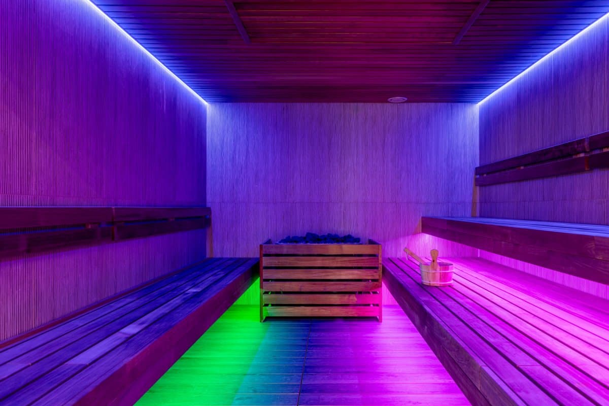 Saună cu iluminare neon violet și bancă din lemn