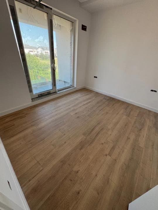 Cameră cu parchet și ușă spre balcon