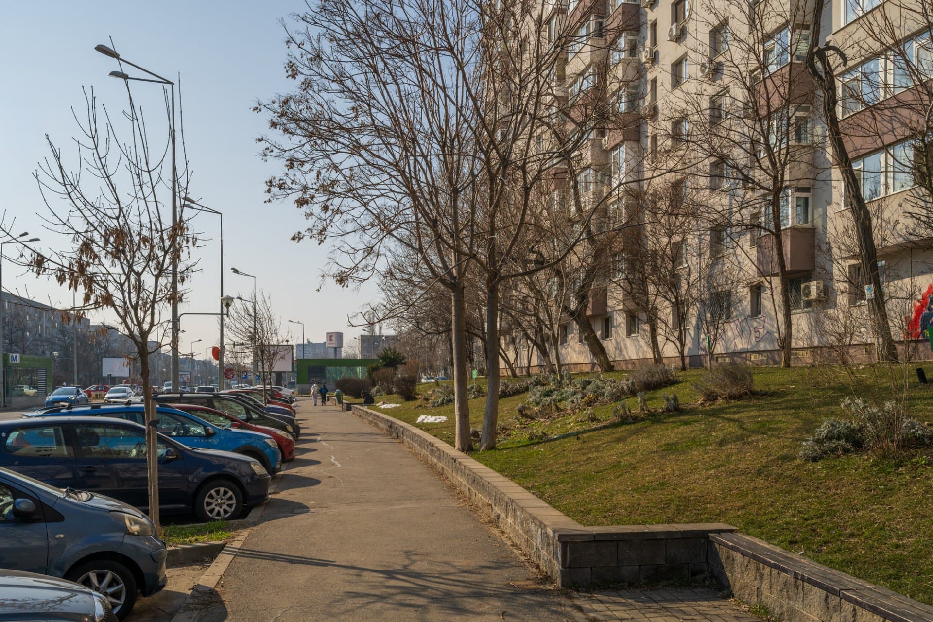 Intrarea complexului cu parcări și copaci