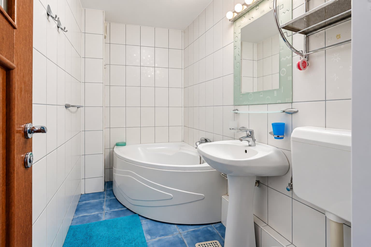 Baie cu cadă înclinată, chiuvetă și faianță albă